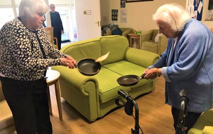two women tossing a pancake between their pans