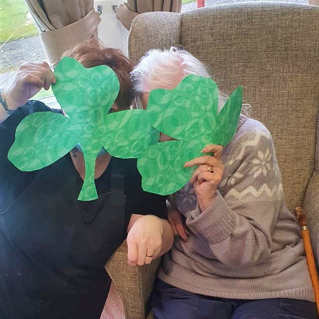 Brookfield - resident and staff holding shamrock cut outs in front of their faces