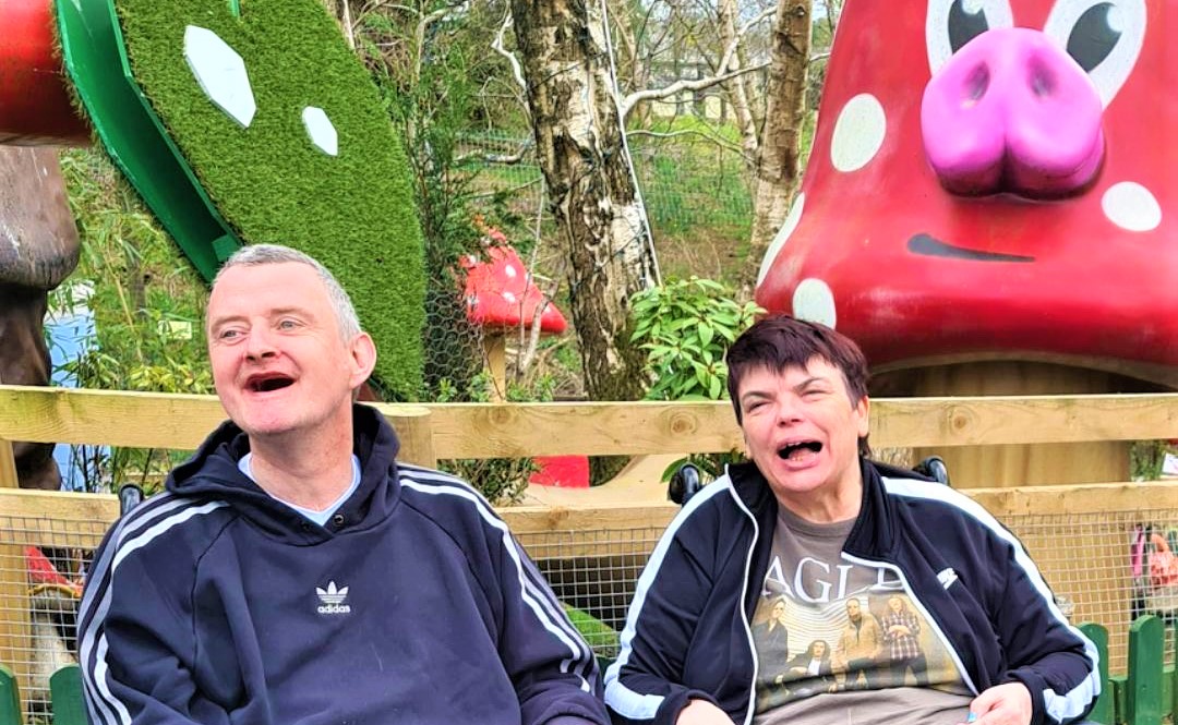 two residents laughing in front of a giant coloured toadstool