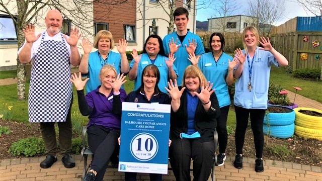 Coupar Angus - staff group with hands raised outside care home