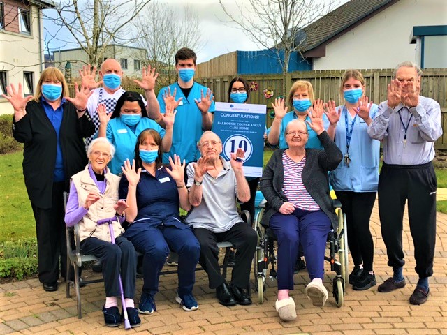 Coupar Angus - staff group and residents with hands raised outside care home