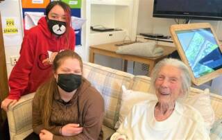 two young students with care home resident laughing