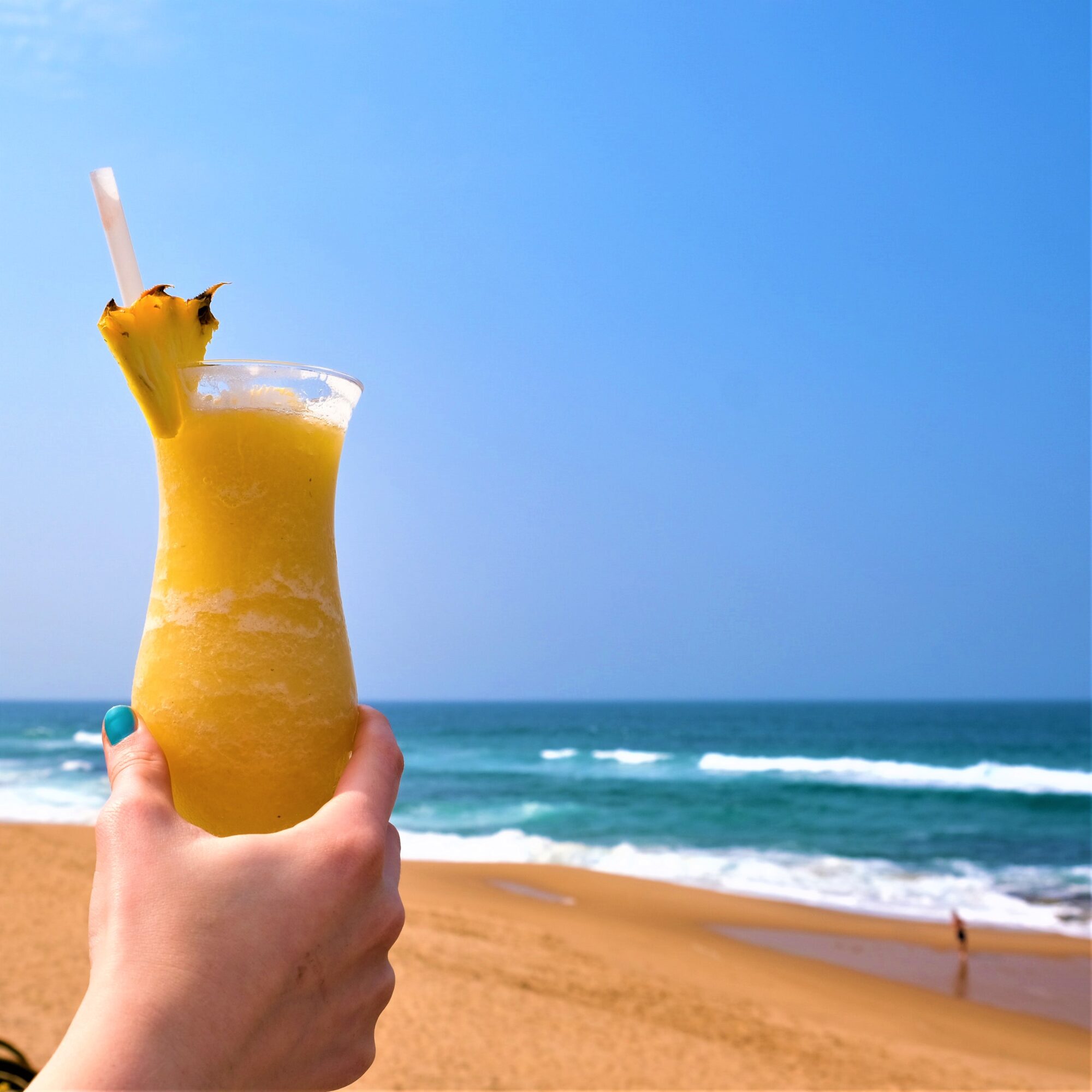 pina colada in a glas in front of a beach view