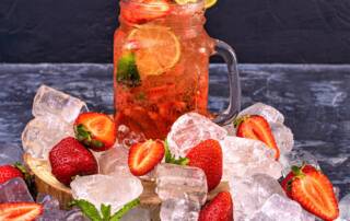 Glass of Pimms with ice and strawberries and on the surface