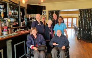 Carers and residents in a pub - two at front in wheelchairs