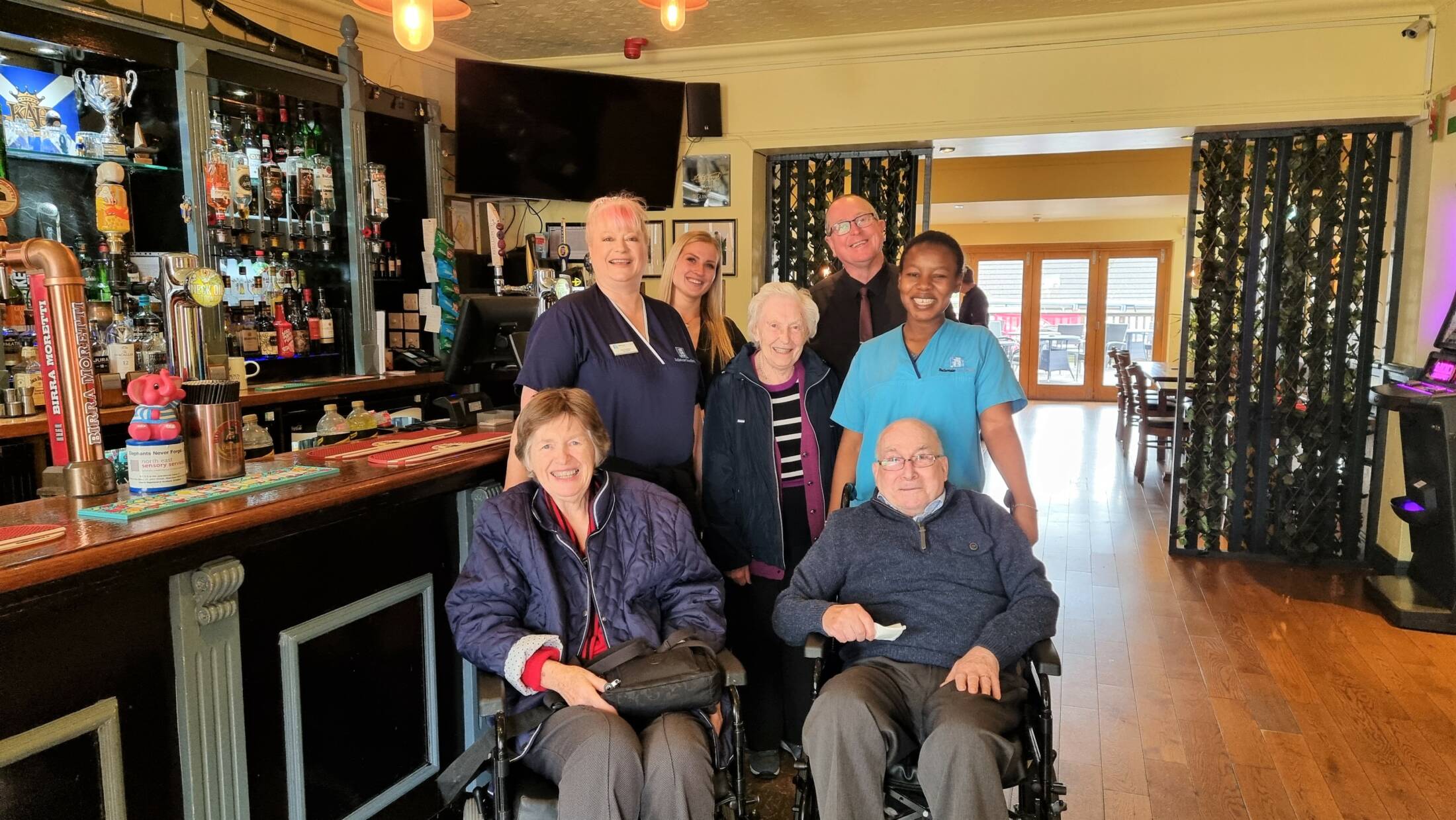 Carers and residents in a pub - two at front in wheelchairs