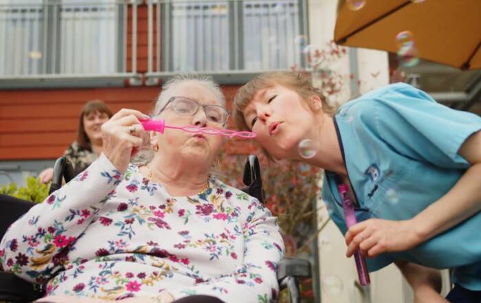 resident and carer blowing bubbles